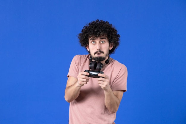 vista frontal jogador masculino jogando videogame com gamepad no fundo azul jovem adolescente virtual vencedor alegria jogador juvenil vídeo futebol adulto