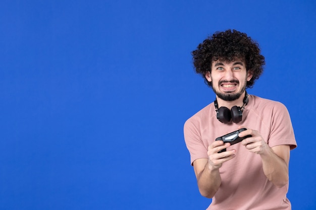 vista frontal jogador masculino jogando videogame com gamepad no fundo azul vencedor adolescente futebol adulto alegria jogador jovem virtual