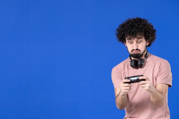 vista frontal jogador masculino jogando videogame com gamepad no fundo azul vencedor adolescente jogador adulto futebol alegria jovem sofá virtual jovem