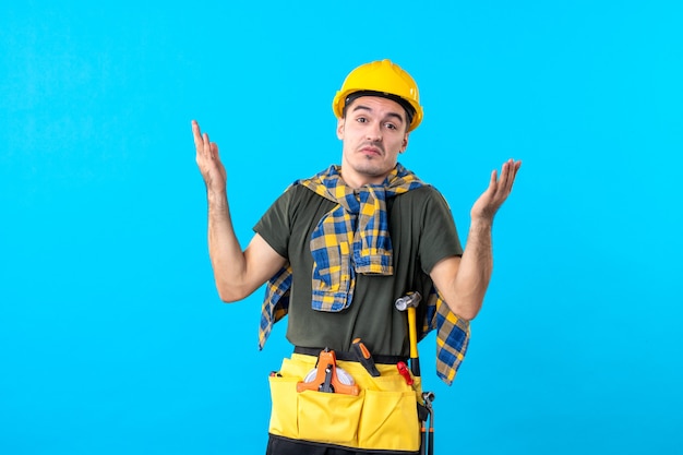 vista frontal jovem construtor masculino com capacete amarelo sobre fundo azul ferramenta cor plana arquitetura trabalhador de construção