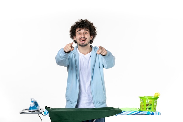 vista frontal jovem do sexo masculino atrás da tábua de passar no fundo branco trabalho doméstico emoção cor humana lavanderia lavagem a seco