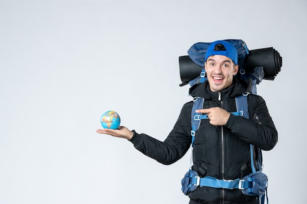 vista frontal jovem do sexo masculino com mochila segurando o globo terrestre no fundo branco campanha acampamento acampamento neve fria céu montanha floresta ar