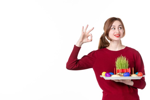 vista frontal jovem fêmea segurando honca com semeni e novruz doces no fundo branco primavera artista étnica férias conceito família cores