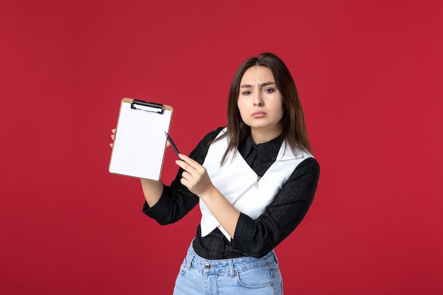 Vista frontal jovem garçonete segurando o bloco de notas para pedidos no fundo vermelho trabalho comida trabalho refeição beleza trabalhador noite mulher cores jantar