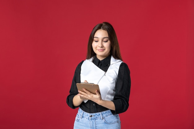 vista frontal jovem garçonete uniformemente escrita ordem no fundo vermelho beleza mulher jantar trabalho noite trabalho restaurante trabalhador