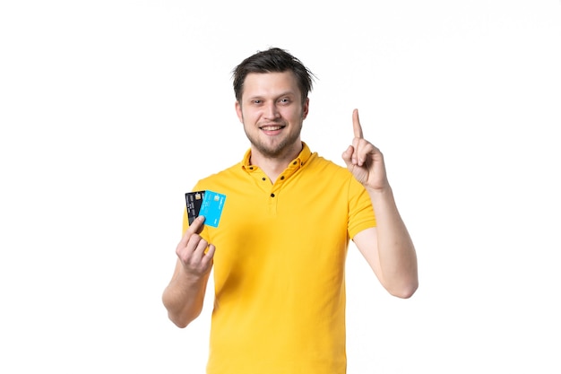 vista frontal jovem homem de camisa amarela segurando um par de cartão do banco no fundo branco uniforme trabalho trabalhador gastando dinheiro cores humanas