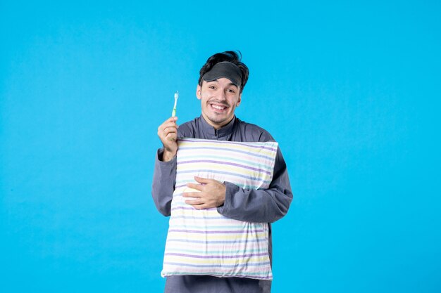 vista frontal jovem homem de pijama escovando os dentes antes de dormir no fundo azul cor do pesadelo descanso humano acordar limpar a cama noite