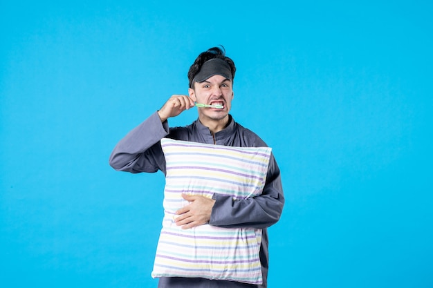 vista frontal jovem homem de pijama escovando os dentes antes de dormir no fundo azul tarde cor resto humano acordar cama pesadelo sonhos dormir