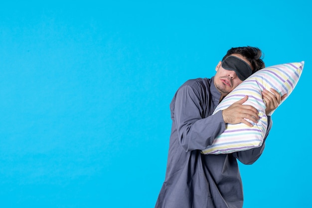 vista frontal jovem homem de pijama tentando adormecer no travesseiro sobre fundo azul cor de fundo descanso humano acordar noite noite pesadelo sonho sono