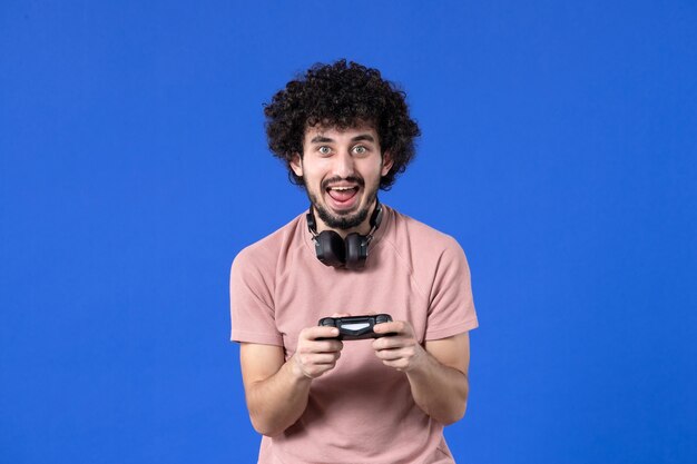 vista frontal jovem jogando videogame com gamepad preto sobre fundo azul adolescente adolescente jogador vencedor futebol adulto virtual