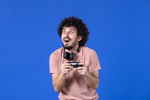 vista frontal jovem jogando videogame com gamepad preto sobre fundo azul sofá virtual adolescente jovem jogadores de futebol adulto ganhando alegria