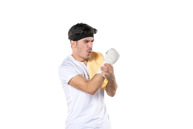 vista frontal jovem macho com bandagem na mão machucada no fundo branco ajuste ginásio atleta dor estilo de vida esporte dieta lesão