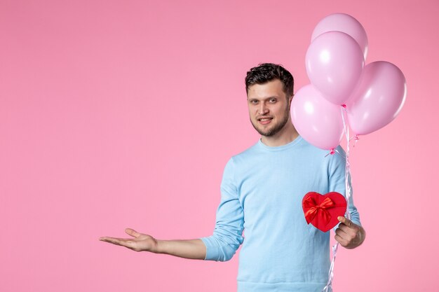 vista frontal jovem macho com bonitos balões rosa e coração em forma de presente no fundo rosa amor sensual igualdade dia das mulheres casamento março feminino parque data