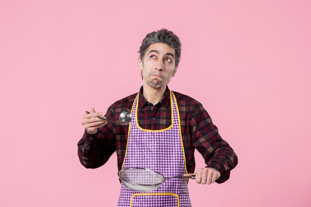 vista frontal jovem macho na capa com peneira e colher no fundo rosa trabalhador uniforme comida marido cozinha horizontal cozinha sopa profissão