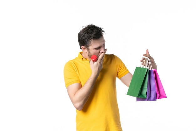 Foto vista frontal jovem macho segurando halteres e pacotes no fundo branco cor esporte uniforme humano dinheiro trabalhador trabalho compras