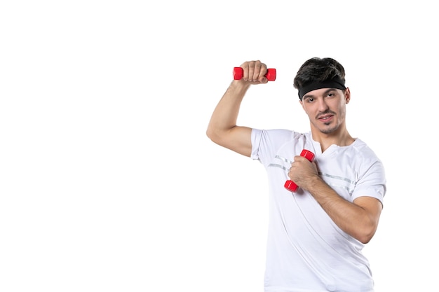 vista frontal jovem macho segurando halteres vermelhos no fundo branco atleta ioga estilo de vida dieta cor saúde esporte apto humano