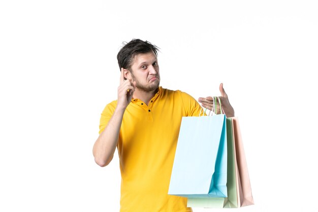 vista frontal jovem macho segurando pacotes de compras no fundo branco ginásio trabalho vendedor uniforme dinheiro compras saúde