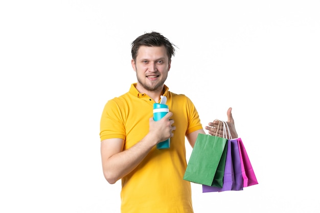 vista frontal jovem macho segurando pequenos pacotes e garrafa térmica no fundo branco cor esporte uniforme humano dinheiro trabalhador trabalho compras