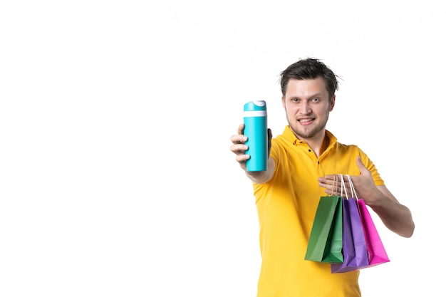 vista frontal jovem macho segurando pequenos pacotes e garrafa térmica no fundo branco trabalho cor esporte uniforme humano vendedor compras água