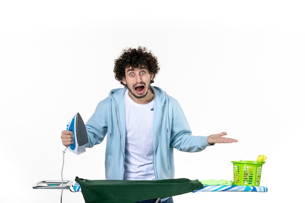vista frontal jovem masculino engomar camisa verde sobre fundo branco trabalho doméstico emoção ferro humano lavanderia roupa para lavagem a seco