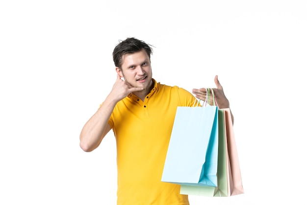 vista frontal jovem masculino segurando pacotes de compras no fundo branco ginásio trabalho vendedor uniforme compras saúde esporte