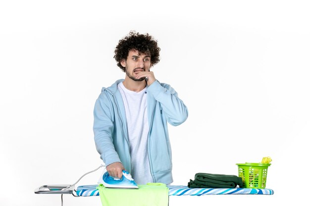 Vista frontal jovem masculino toalha de engomar a bordo sobre fundo branco ferro cor homem limpeza foto roupas trabalho doméstico