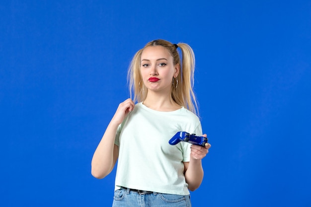 vista frontal jovem mulher com gamepad no fundo azul jogador adulto sofá online vídeo vencedor jovem alegre virtual