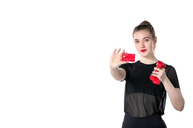 vista frontal jovem mulher com halteres e cartão do banco nas mãos na mesa branca ginásio dinheiro corpo atleta esporte estilo de vida saúde