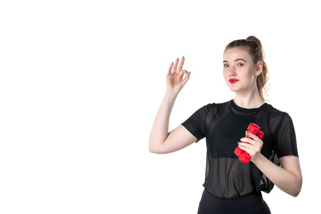 vista frontal jovem mulher com halteres nas mãos no fundo branco ginásio circo corpo atleta esporte estilo de vida ioga saúde