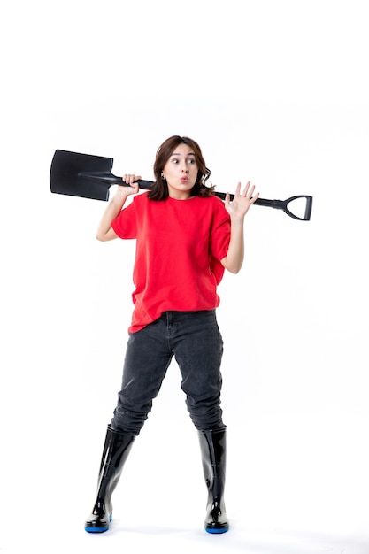 vista frontal jovem mulher de camisa vermelha segurando uma pá preta no fundo branco mulher solo limpo cemitério cor emoção escavação