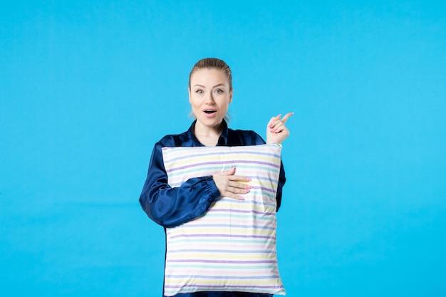 vista frontal jovem mulher de pijama segurando travesseiro sobre fundo azul cor da mulher dormir noite cama sonho pesadelo bocejo