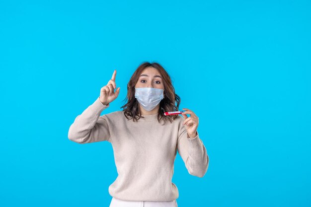 vista frontal, jovem, mulher, máscara, com, frasco, sobre, azul, fundo, ciência, médico, vírus, covid, pandemia, doença, saúde, isolamento