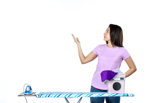 Vista frontal joven ama de casa con ropa y tabla de planchar sobre fondo blanco emoción seca quehaceres domésticos mujer limpia trabajo de color