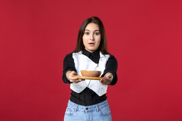 Vista frontal joven camarera sosteniendo pedidos de comida sobre fondo rojo trabajo comida trabajo comida belleza trabajador noche mujer color uniforme