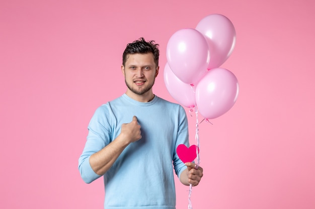 Vista frontal joven con globos lindos y pegatina de corazón sobre fondo rosa igualdad día de la mujer fecha de matrimonio marzo sensual femenino divertido amor