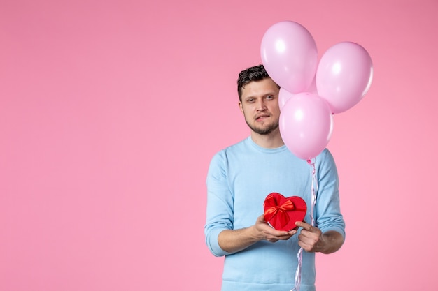 Vista frontal joven con lindos globos rosados y presente en forma de corazón sobre fondo rosa igualdad día de la mujer marcha de matrimonio sensual femenino divertido parque de amor