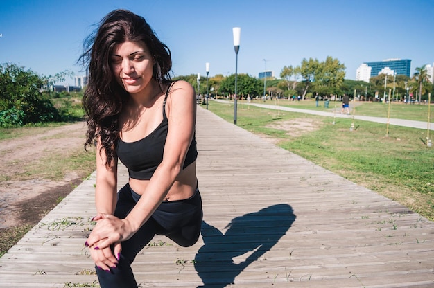 Vista frontal joven mujer caucásica latina entrenando estirando las piernas al aire libre