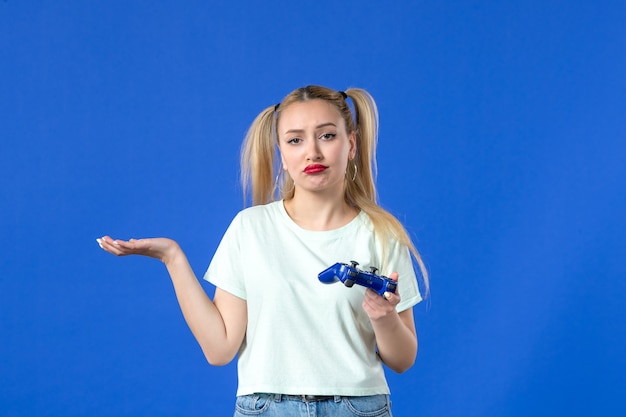 Vista frontal joven mujer con gamepad sobre fondo azul alegre video adulto joystick online jugador juvenil virtual
