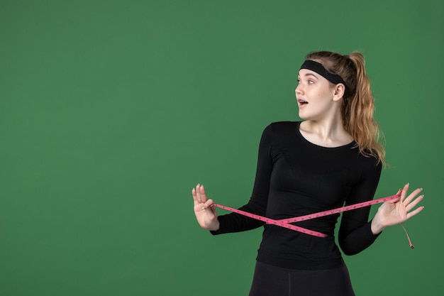 Vista frontal joven mujer midiendo su cuerpo con centímetro sobre fondo verde atleta negro mujer color salud ajuste deporte entrenamiento