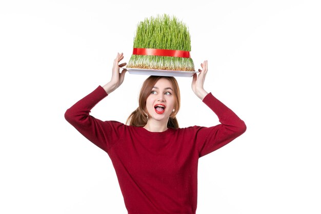 vista frontal joven mujer sosteniendo gran verde novruz semeni en su cabeza sobre fondo blanco primavera étnico ejecutante etnia concepto colores vacaciones familia