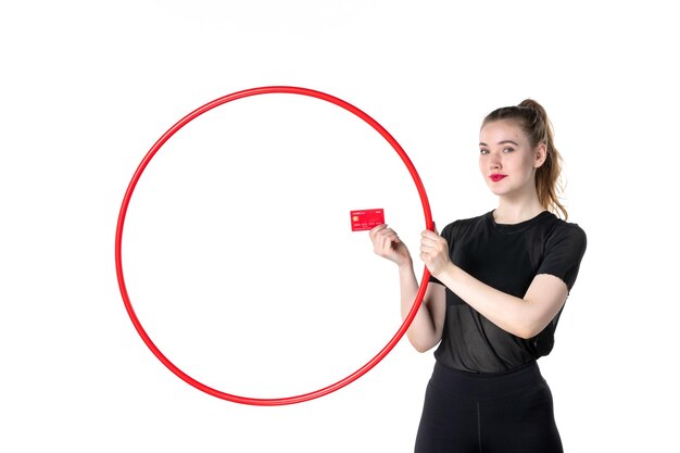 Foto vista frontal joven mujer sosteniendo hula hoop y tarjeta bancaria sobre fondo blanco yoga cuerpo estilo de vida deporte salud atleta circo dinero gimnasio