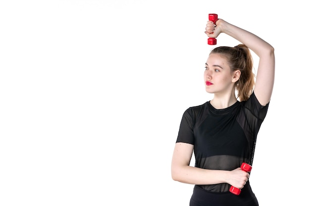 Vista frontal joven mujer trabajando con pesas sobre fondo blanco circo yoga cuerpo salud atleta gimnasio estilo de vida