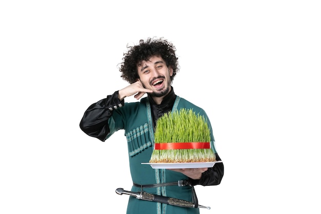 Vista frontal del joven sonriente en traje tradicional azerbaiyano sosteniendo semeni sobre fondo blanco artista novruz etnia primavera concepto bailarín