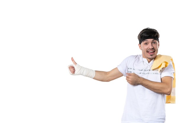 Vista frontal joven con vendaje en su mano herida sobre fondo blanco dieta deporte dolor estilo de vida lesión en forma atleta gimnasio cuerpo