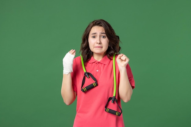Vista frontal joven vendedora con vendaje en su mano herida sobre fondo verde trabajo color salud hospital compras trabajo uniforme