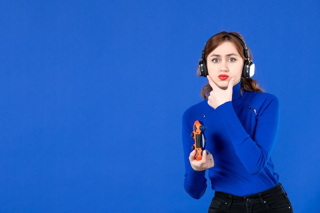 Vista frontal jugador femenino con gamepad jugando videojuegos sobre fondo azul jugador ganador adulto virtual joven joven alegre video ganador alegría