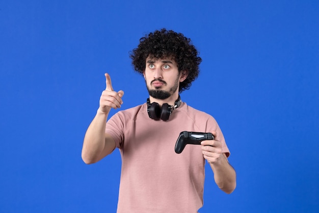 Vista frontal jugador masculino con gamepad sobre fondo azul joven jugador de alegría adolescente virtual juvenil video de fútbol para adultos