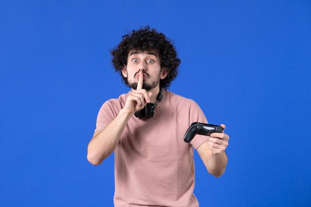 Vista frontal jugador masculino con gamepad sobre fondo azul joven jugador de fútbol virtual adolescente ganando alegría video