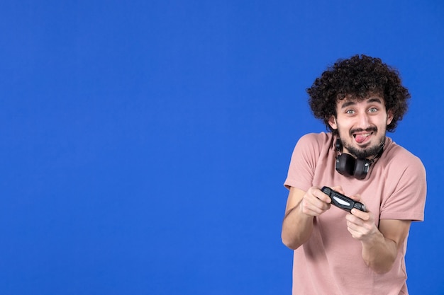 vista frontal jugador masculino jugando videojuegos con gamepad fondo azul fútbol adulto alegría sofá joven adolescente ganador virtual juventud