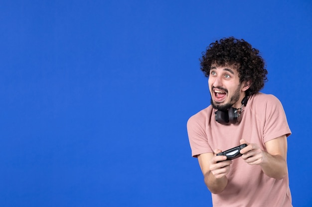 vista frontal jugador masculino jugando videojuegos con gamepad fondo azul fútbol adulto alegría sofá jugadores joven ganador adolescente virtual juventud